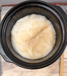 soap batter in a slow cooker with a very thick consistency and foam forming around the edges looking like it has formed partially solidly on the top